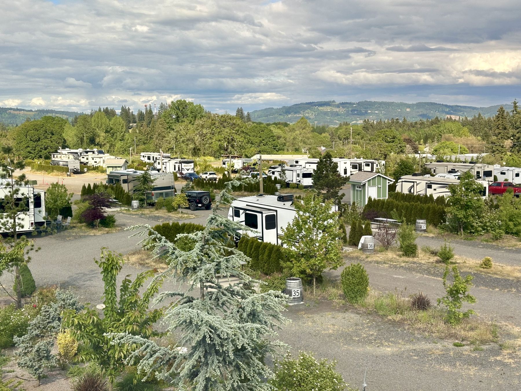The image shows a campground or RV park with multiple RV trailers surrounded by trees and natural scenery in Dundee, OR.