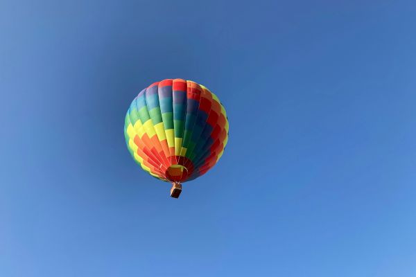 A colorful hot air balloon floats against a clear blue sky, creating a vibrant and serene scene.