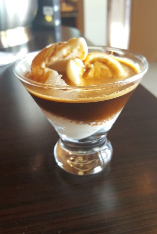 This image shows a dessert glass with vanilla ice cream topped with a shot of espresso, commonly known as an affogato.